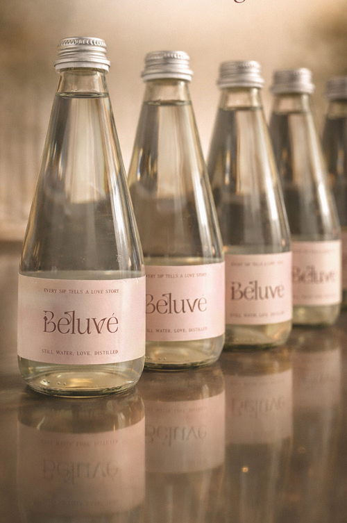 Beluvé water bottles on a reflective surface with a blurred background